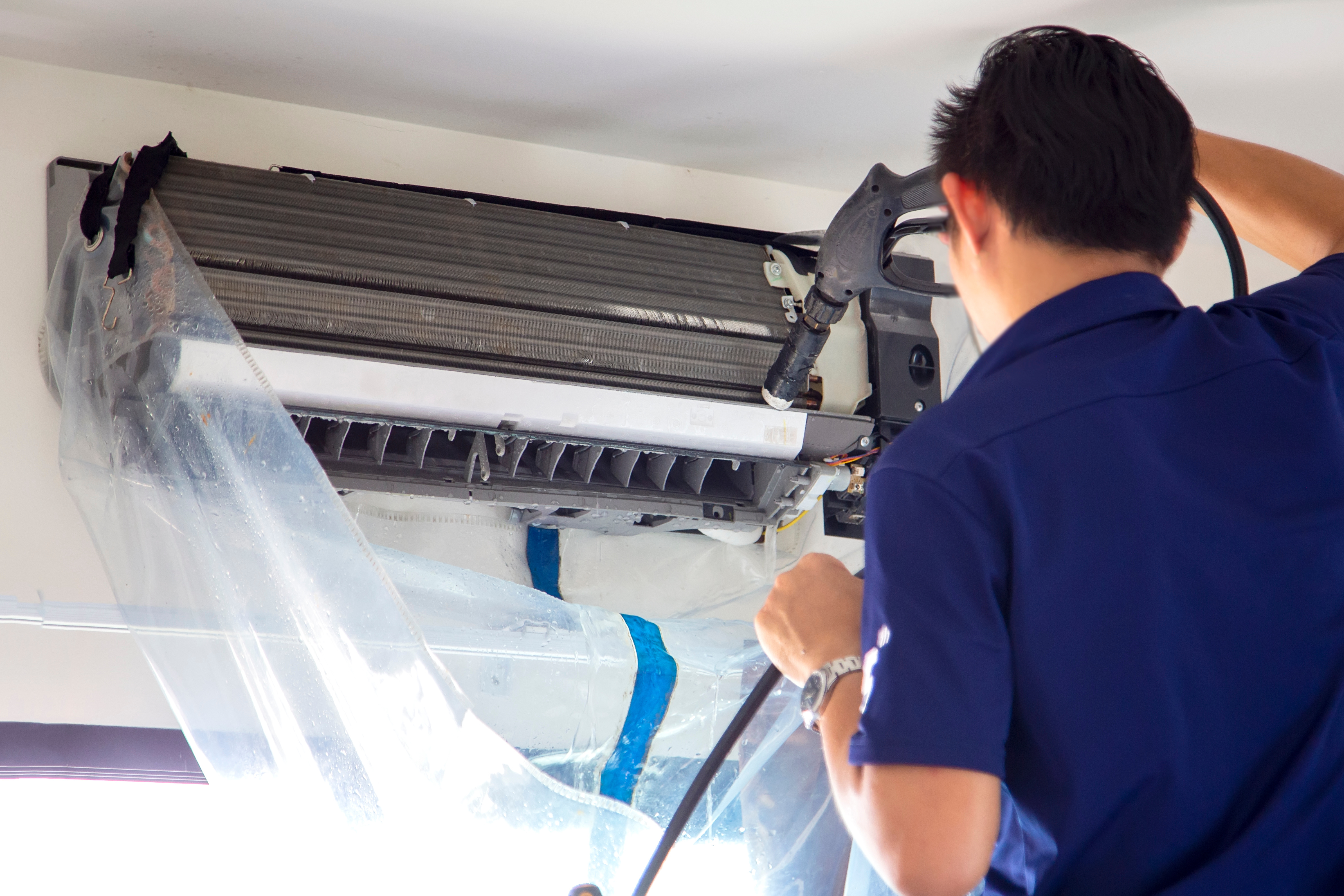 The technicians are cleaning the air conditioner by spraying wat